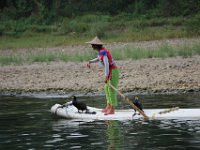 Dame på bambusbåd med et par Skarve som er trænet til at fange fisk.